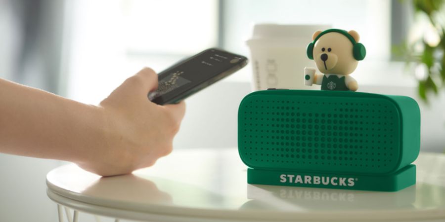 Adventure Tourism-How Hospitality Can Win Travellers with Scuffed Boots and Green Hearts 5 A young adventure traveler using a smartphone and a high-tech tablet to plan a trip or upload adventure photos, with a map and camera on a rustic wooden table.