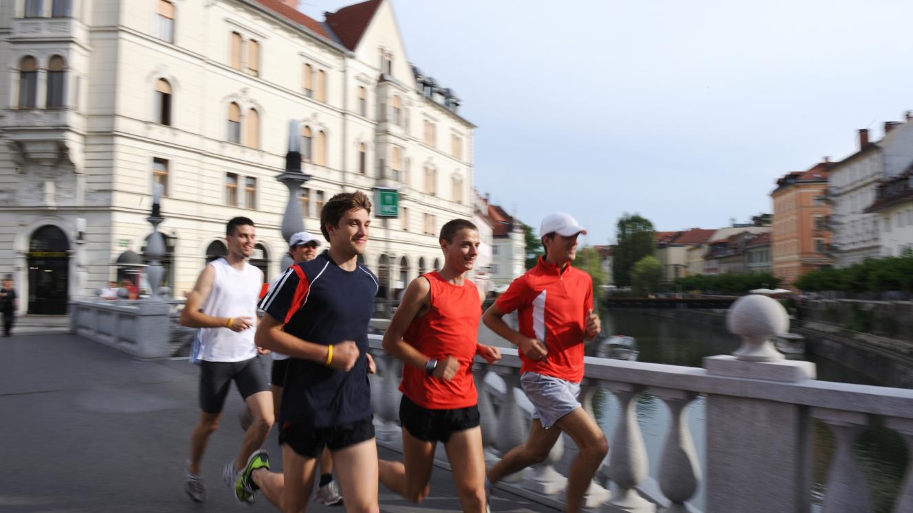 Adventure Tourism-How Hospitality Can Win Travellers with Scuffed Boots and Green Hearts 3 A group of young men in athletic gear running across a stone bridge in a European city during a Contiki active travel tour.