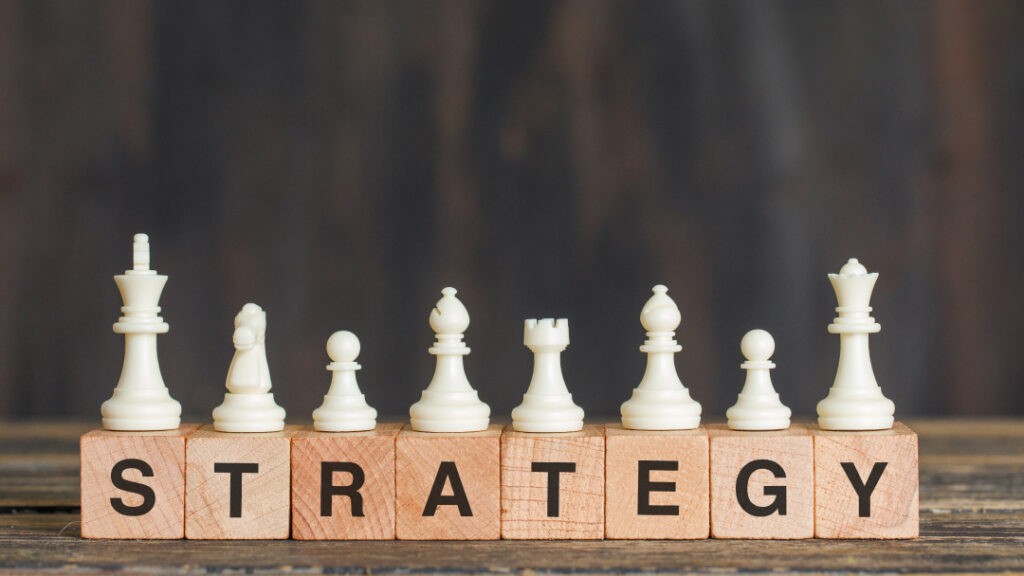 "White chess pieces standing on wooden blocks that spell out the word STRATEGY, symbolizing a planned approach to voice search SEO."