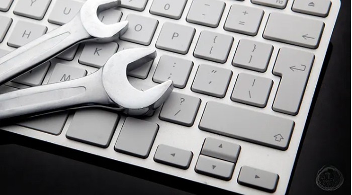 Two silver metal wrenches laying on a white computer keyboard, symbolizing website optimization and technical SEO."